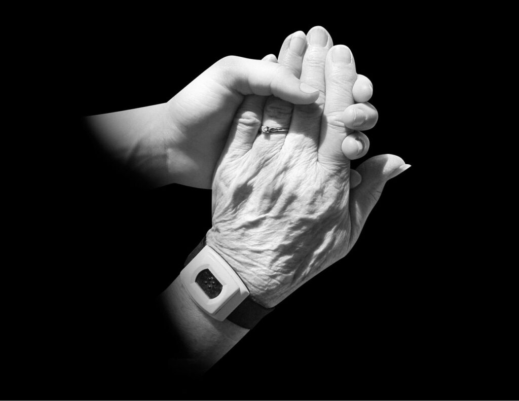 Main d'un jeune tenant la main d'une personne âgée